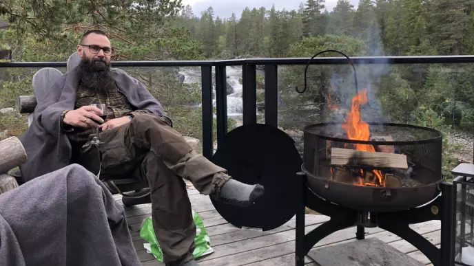 Skogfar koser seg med litt saft og kontrollert bål i panne. I bakgrunnen ser du fossen som hadde litt å fortelle oss.